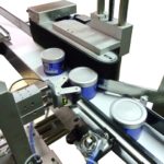 Dispositivo rotazione con rulli di contrasto integrato su sistema di etichettatura con rotolatore continuo