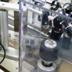 Dispositivo rotazione con rulli di contrasto integrato su sistema di etichettatura con rotolatore continuo per alte velocità